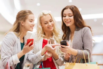 girls watch smartphones while shopping
