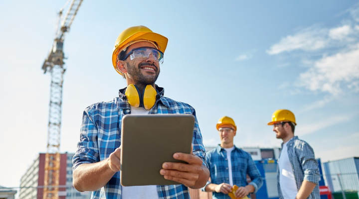 Operador en el sitio de construcción con una tableta en mano