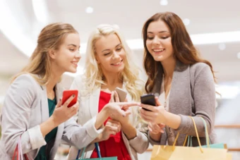 ragazze guardano smartphone mentre fanno shopping