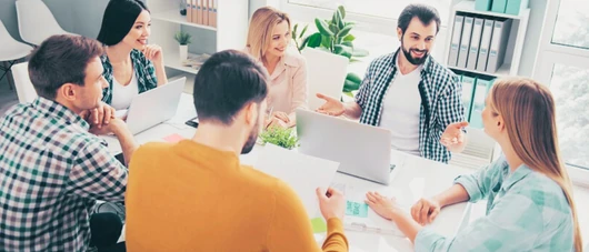 equipo colabora alrededor de una mesa de trabajo