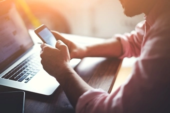 hombre en pc consulta smartphone