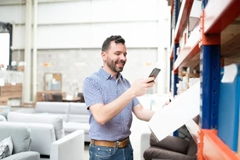 an employee checks the goods in the warehouse with a smartphone