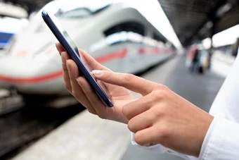 man using mobile application on his smartphone at train station, business travel